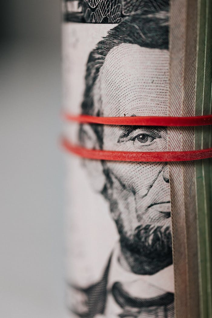 Over Ons Closeup of rolled United States five dollar bills tightened with red rubber band